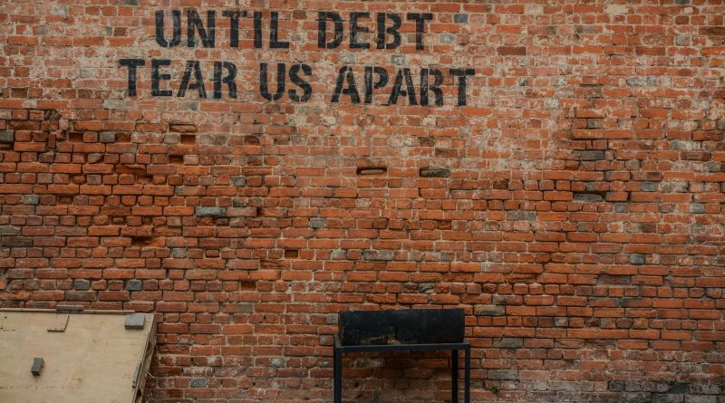 Until debt tear us apart printed red brick wall at daytime