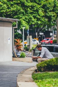 a man sitting on a curb looking at his cell phone