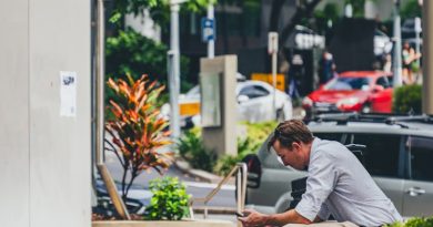 a man sitting on a curb looking at his cell phone