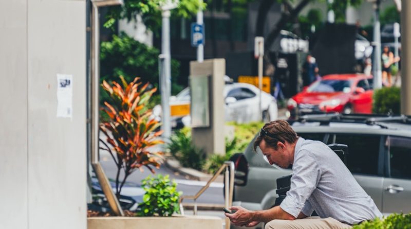 a man sitting on a curb looking at his cell phone